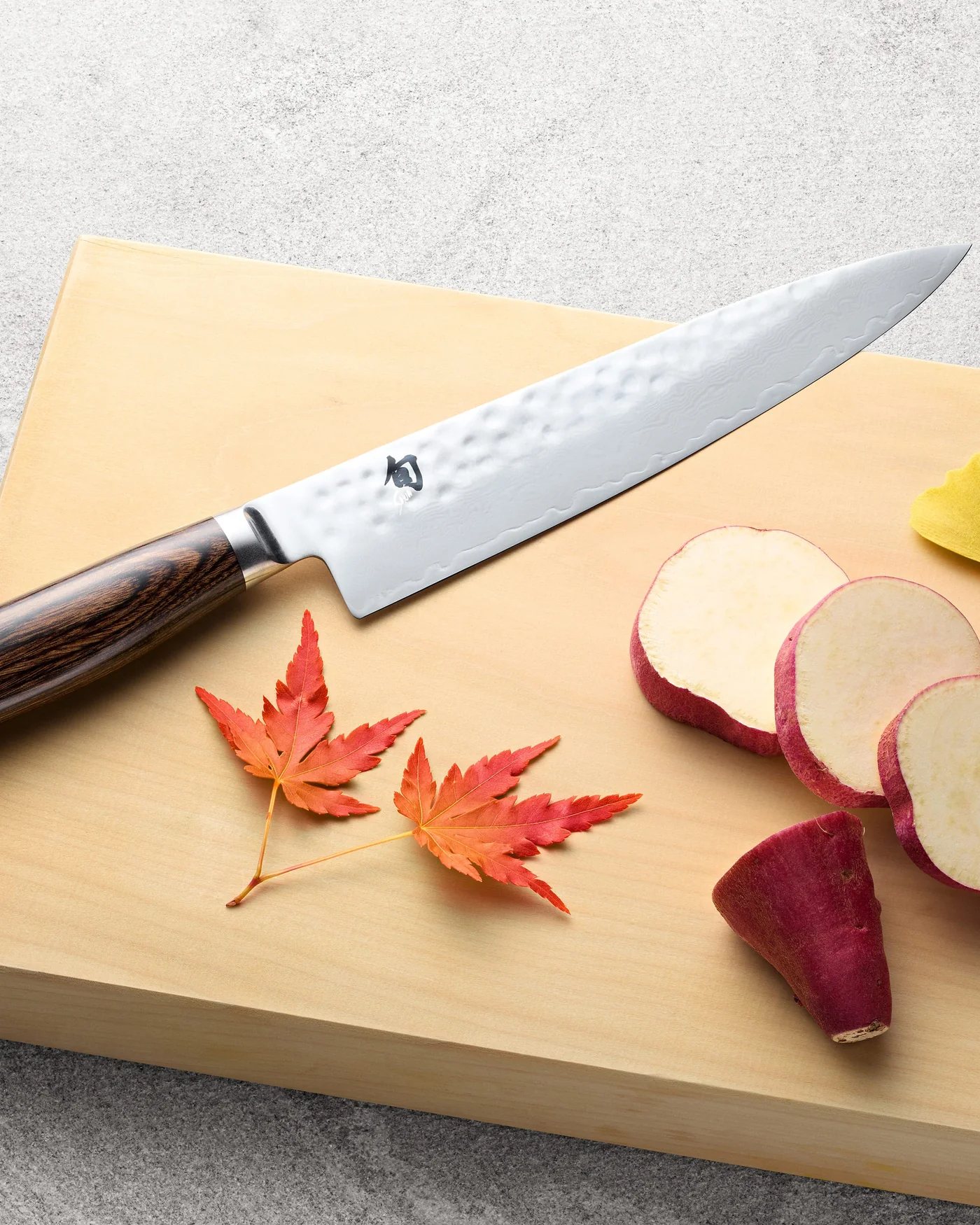 Shun Premier chef’s knife on a wooden board with sliced sweet potato and autumn leaves